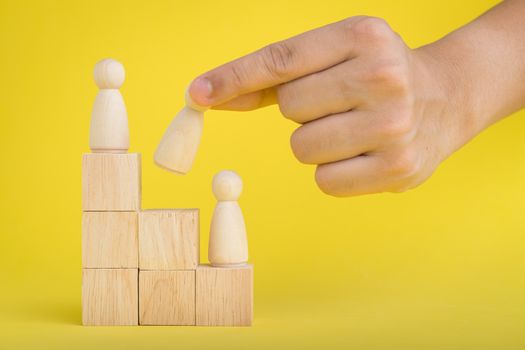 The hand is picking or select wood figure on the wooden Stacked in human resource management concepts Teamwork.Success Leadership,Business Progress and Competition on yellow backgrond and copy space