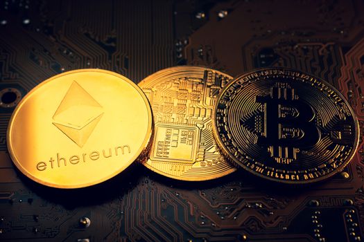 Golden coins with ethereum and bitcoin symbol on a mainboard.