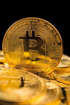 Golden coins with bitcoin symbol on a black background.