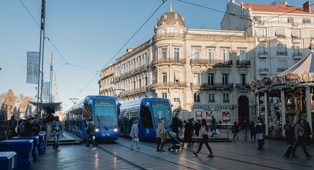 Montpellier, France - January 2, 2019: Electric tram stopped at Place de la Comedie where people pass on a winter day