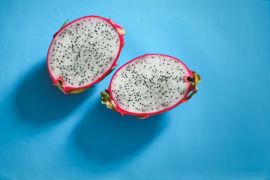 Fresh sliced dragonfruit or pitaya against a bright blue background to show color contrast, concept of fun, summer and pop culture