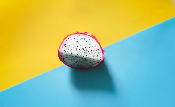 Fresh sliced dragonfruit or pitaya against a bright blue and yellow background to show color contrast, concept of fun, summer and pop culture