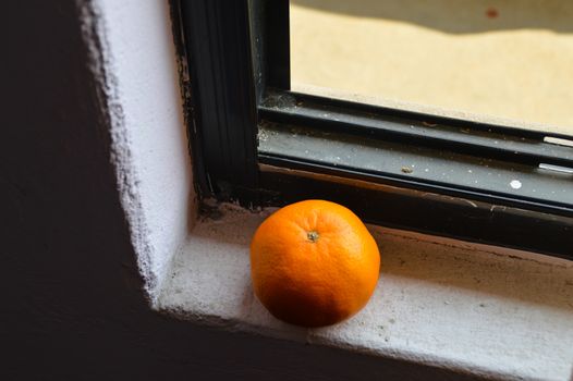 An orange fruit on the window sill, showing concept of wellness, mindfulness and wellbeing