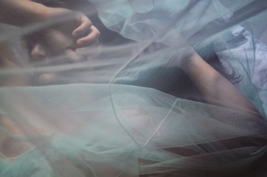 Conceptual photo of a man half hidden by a thin veil showing the concept of gender identity, intimacy and sensuality