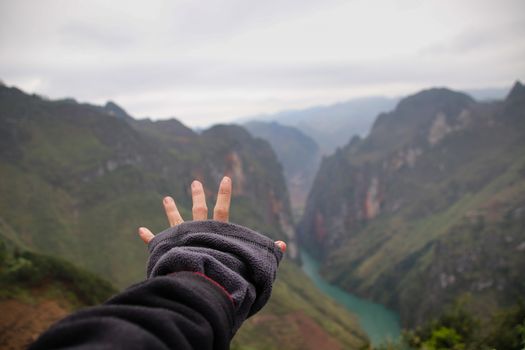 Hand reaching out to the majestic landscape of Dong Van in Vietnam