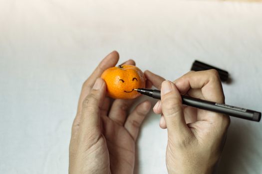 Conceptual photo showing an orange with a smiley face to show the concept of happiness, choosing happiness, positivity and mental health