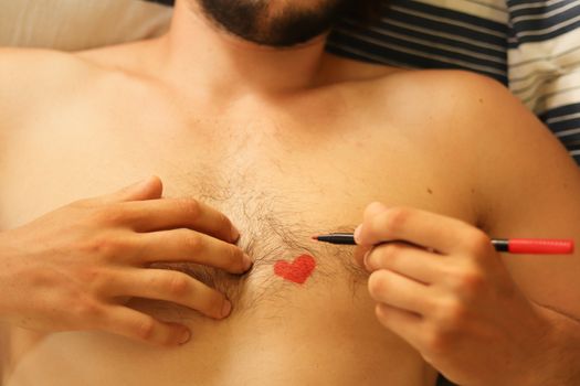 Close up of a heart drawing on a naked male chest showing the concept of vulnerability, falling inlove and gender