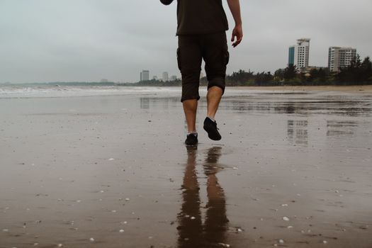 One man walking out into the distance at the shore on a dark gloomy day after a storm