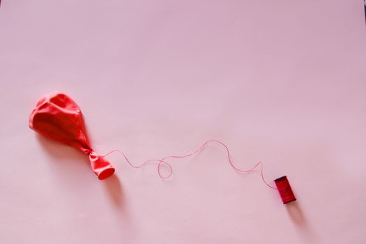 Pink plastic balloon against a pink colored background
