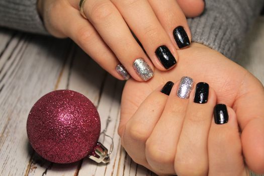 Christmas Nail art manicure. Winter Holiday style bright Manicure with gems Christmas tree and snowflakes. Bottle of Nail Polish.