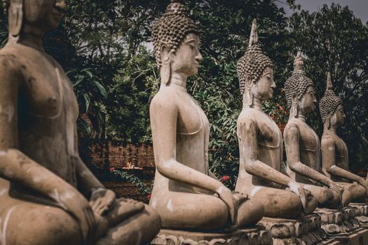 Buddha stone statues in a row at the famous Ayutthaya Historical Park which is a popular tourist destination to experience thai culture, religion and history
