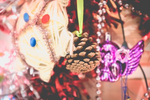 Christmas decoration made by children garlands, balls and pine cone on a fir tree made from wooden board at home