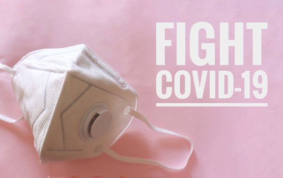 N95 mask against a pink background with the words Fight Covid-19 written on it to raise awareness in fighting the corona virus global pandemic crisis