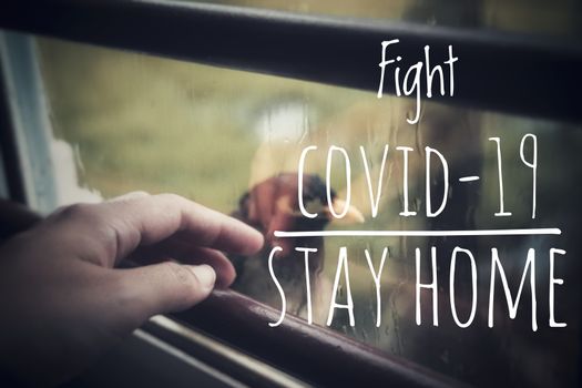 A person looking at a bird outside the window to show the concept of home quarantine and social distancing in the fight against the spread of covid-19 pandemic
