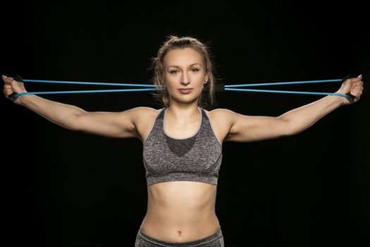 athletic woman stretches elastic rubber behind her head, close up