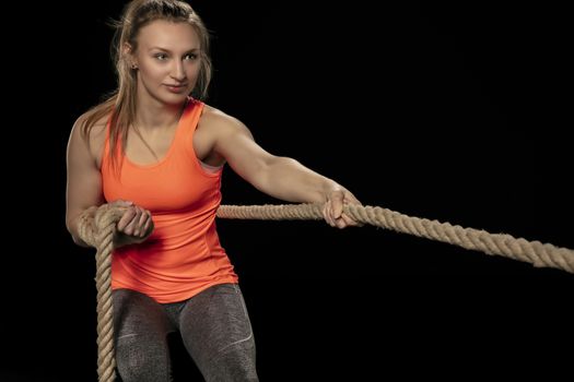 athletic girl exercising with a thick rope