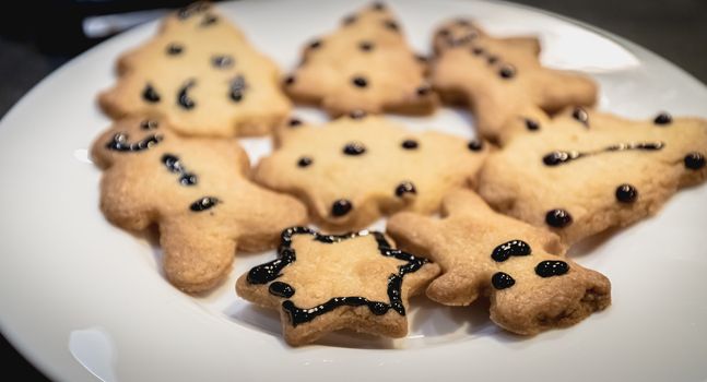 Christmas shortbread cookies in the shape of fir trees, stars and snowmen in a white plate