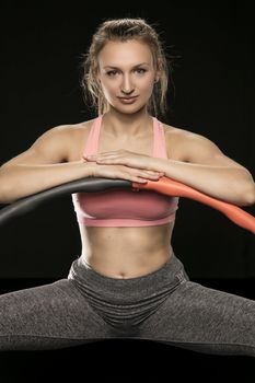 athletic woman holding hula hoop in her hands, isolated on the black background