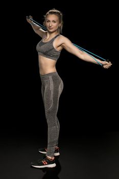 athletic girl stretches and exercises with a flexible rope