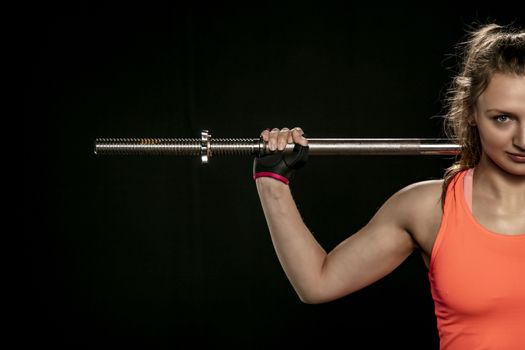 an athletic girl trains with barbells