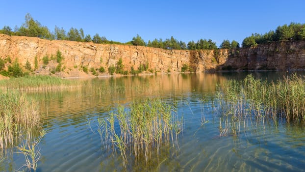 Sandstone cliffs by the pond in an old quarry in Grodek park in Jaworzno, Poland