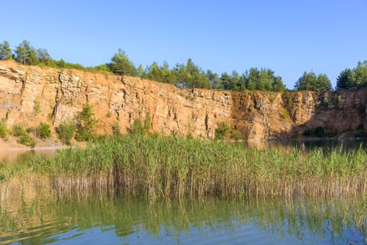 Sandstone cliffs by the pond in an old quarry in Grodek park in Jaworzno, Poland