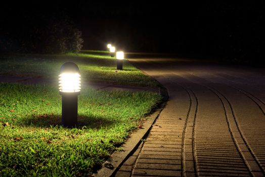 Alley illuminated by the garden lamps in the night