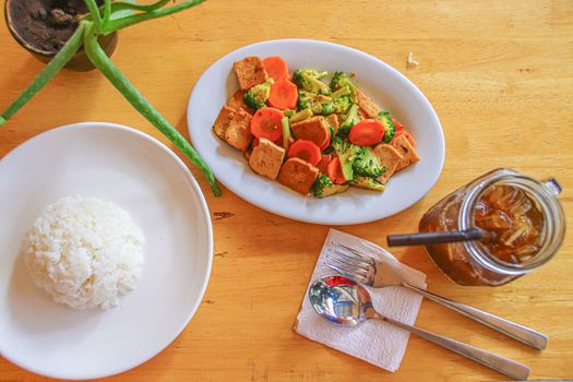 Stir fried tofu, broccoli and carrots with steamed white rice and ice coffee for a healthy vegan lunch as a way to stay fit and healthy during home quarantine due to covid-19