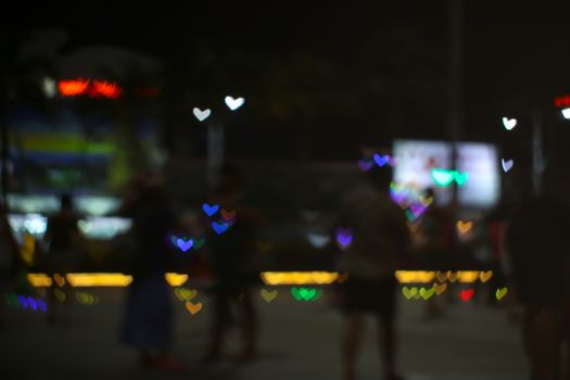blur people selfie with heart shape love valentine's day colorful object on night light of shopping mall