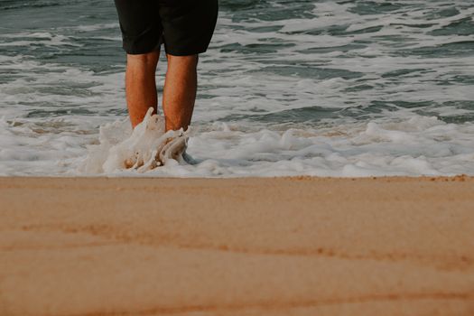 Low section of a man walking on the beach