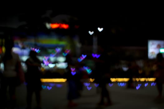 blur people selfie with heart shape love valentine colorful object on night light of shopping mall