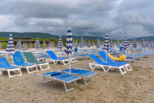 Sunbeds and umbrellas on the calabrian beach on the cloudy evening