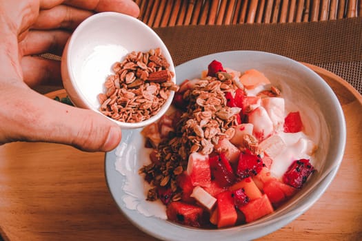 Full vegan breakfast of tropical fruit smoothie bowl with muesli as a way to stay healthy and cope during home quarantine due to the covid-19 pandemic