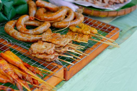 Thai street food. Grilled pork with bamboo stick on green banana leave sell at local market in Thailand.