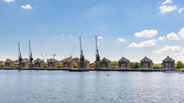 Port cranes and houses at Royal Victoria Dock in London, UK