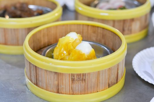 Close up dumpling (Dim sum) in the steam basket. Delicious chinese snack. Boiled Quail egg wrap with wonton sheet on table in restaurant.