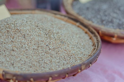 Group of white sesame seeds in bamboo basket sell at Thailand local market.