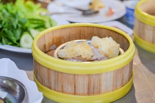 Close up dumpling (Dim sum) in the steam basket. Delicious chinese snack. Steaming minced pork with jelly fish on restaurant.