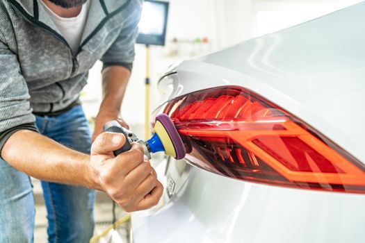 hand polishing car headlights with the help of a hand grinder for better shine.