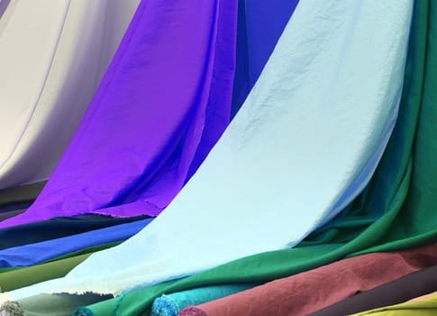 Detailed close up view on samples of cloth and fabrics in different colors found at a fabrics market.