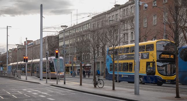 Dublin, Ireland - February 12, 2019: Typical Irish double decker bus running and an electric tram with their passengers in the city center on a winter day