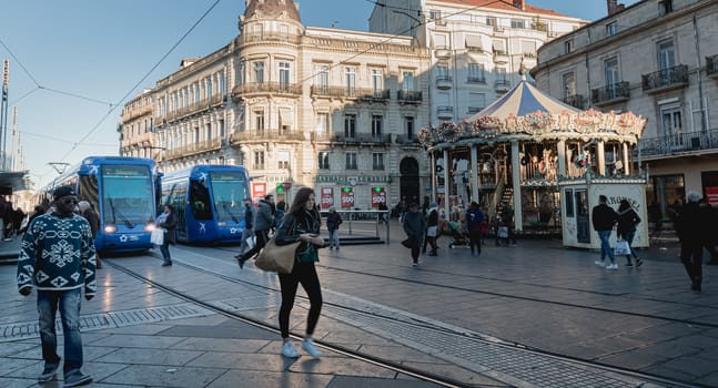 Montpellier, France - January 2, 2019: Electric tram stopped at Place de la Comedie where people pass on a winter day