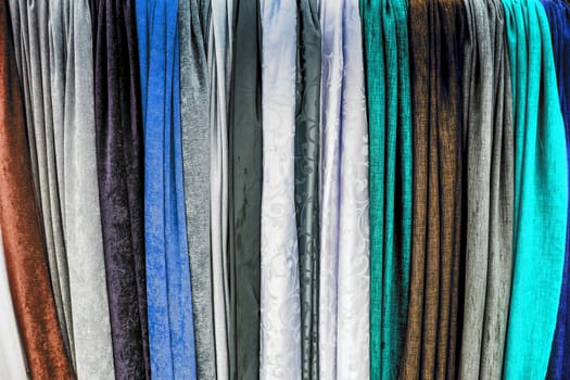 Detailed close up view on samples of cloth and fabrics in different colors found at a fabrics market.