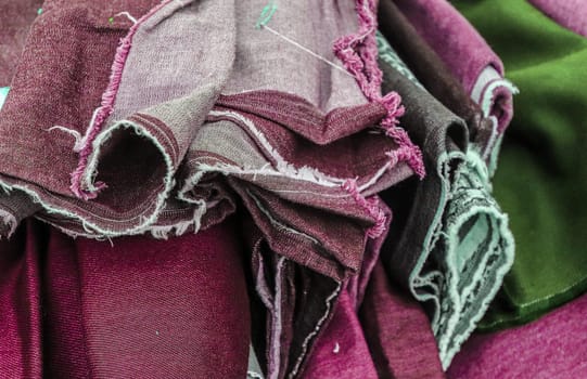 Detailed close up view on samples of cloth and fabrics in different colors found at a fabrics market.