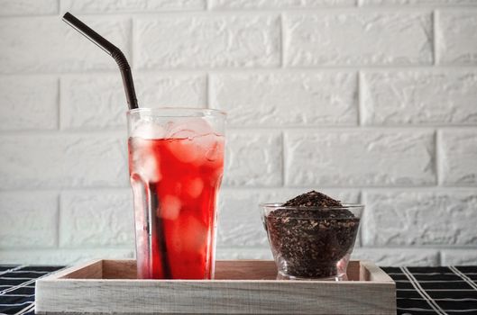 A glass of iced rose tea with dried tea leaf.