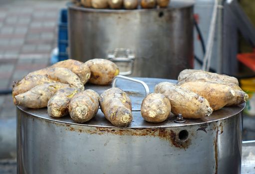 Baked sweet potatoes are kept warm on top of a steel oven
