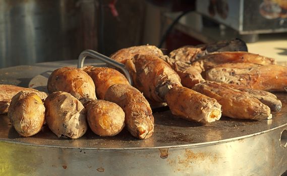 Baked sweet potatoes are kept warm on top of the oven