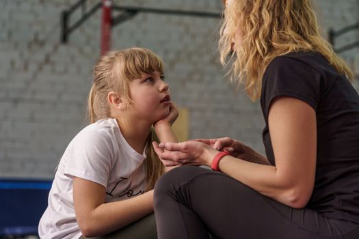 30 years old woman with blond hair talks to her daughter before training in the gym