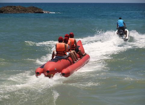 A personal watercraft pulls a large inflatable banana boat
