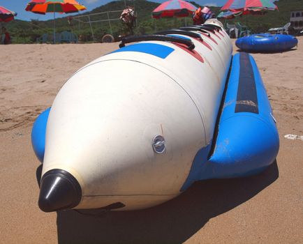 A long banana boat rests on a sand beach
